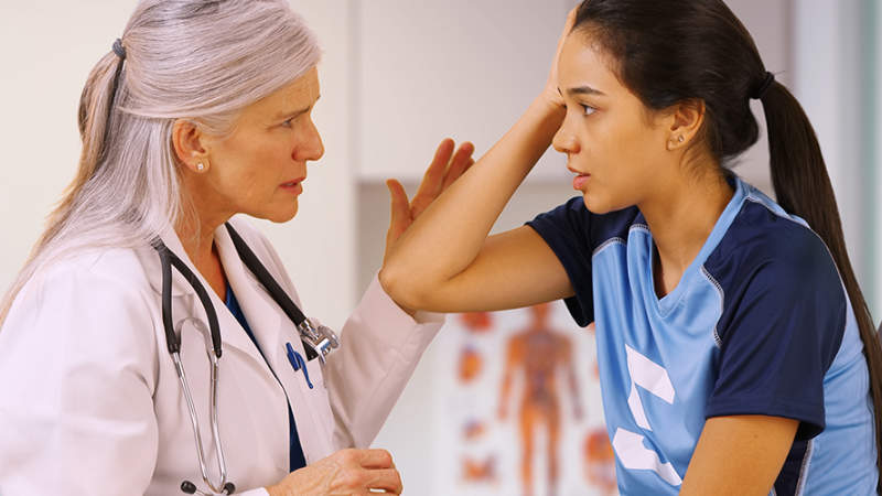 Teen talking to a doctor about a concussion.
