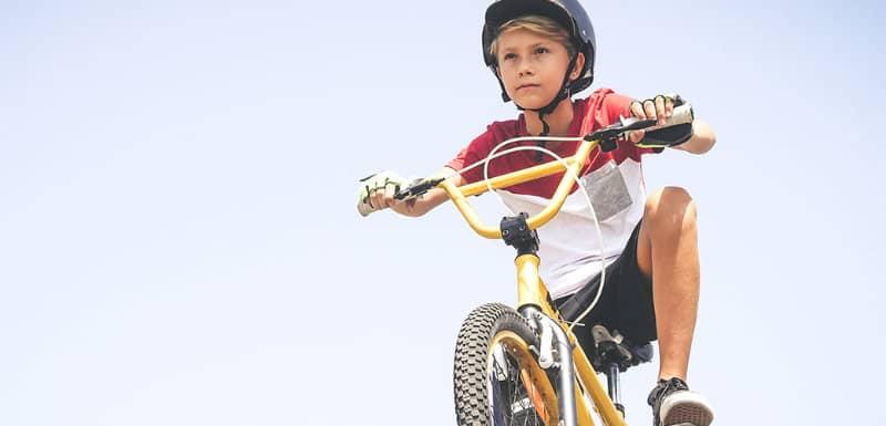 Child wearing a helmet riding a yellow bicycle outdoors.