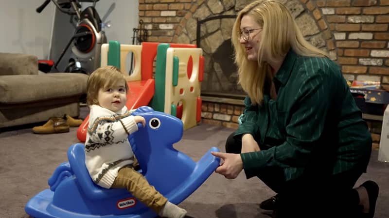 Eric on a blue toy rocking horse next to his Mom.